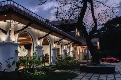 a building with a tree in a courtyard at Mayanadhi Resort in Irimbranallūr