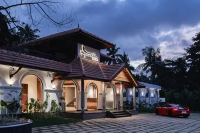 a house with a car parked in front of it at Mayanadhi Resort in Irimbranallūr