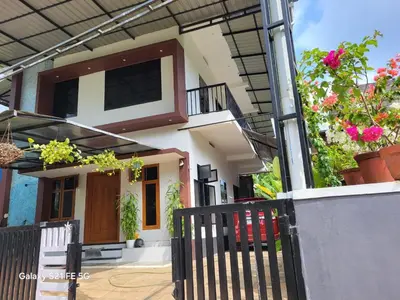 a house with a black fence and some flowers at Home stay in Manjeri