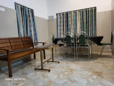 a room with a table and chairs and curtains at Home stay in Manjeri