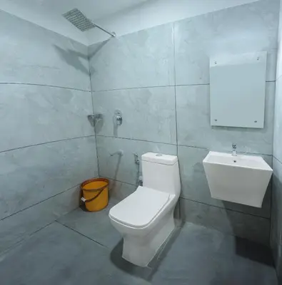 a bathroom with a white toilet and a sink at Munderi Green Mounts - Family Rooms with Swimming Pool in Kalpetta