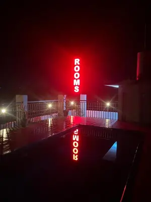 a neon sign is lit up at night at Munderi Green Mounts - Family Rooms with Swimming Pool in Kalpetta