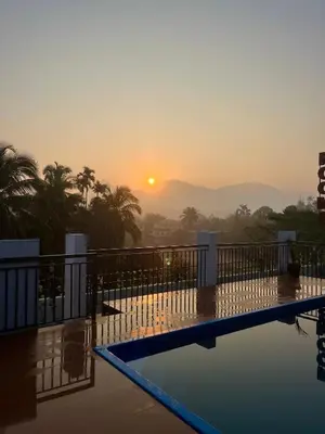 a view of the sunset from a hotel swimming pool at Munderi Green Mounts - Family Rooms with Swimming Pool in Kalpetta