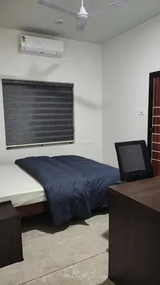 a bedroom with a bed with a window and a desk at Satori Stays - KMA Apartments in Kozhikode
