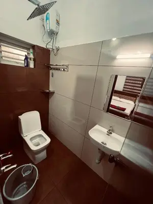 a bathroom with a toilet and a sink and a mirror at Green Villa Chirackal Gardens in Trichūr
