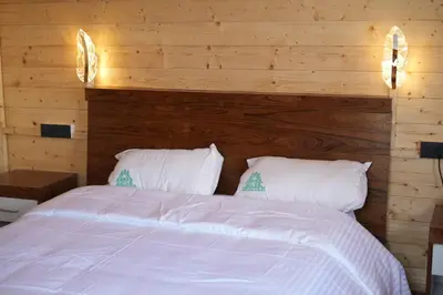 a bedroom with a white bed with wooden walls at Cloudy Nandy Hills Poombarai in Kūkkāl