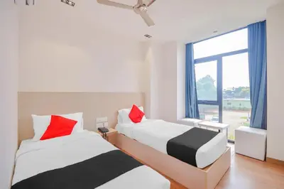 two beds in a room with a large window at capital o hotel paradise international in Coimbatore