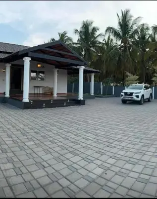 a car parked in front of a building with palm trees at Chettinadu Pool Villa in Pollāchi