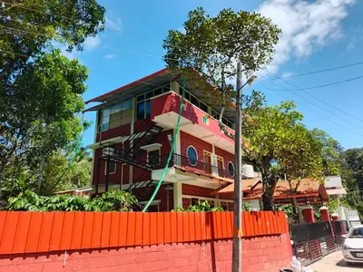 a red building with an orange fence in front of it at JK Cottages in Suntikoppa