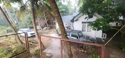 a truck parked in front of a house with a tree at Kodamukku cottage in Trichūr