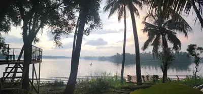 a view of a body of water with palm trees at Kodamukku cottage in Trichūr