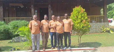a group of men in orange shirts posing for a picture at Jackroot Heritage wood villa Athirappilly in Kallana
