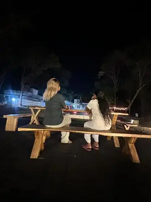 two people sitting on a wooden bench at night at The Cool Cottage at gaya3farms in Palakkad