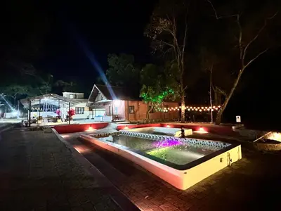 a swimming pool with lights in a yard at night at The Cool Cottage at gaya3farms in Palakkad