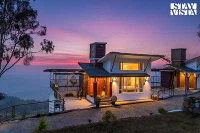 a house with a view of the water at night at Mistydawn Villas By Sunset Valley by VEO - Part of StayVista in Ooty
