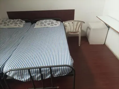 a bed and a chair in a small room at chenniyappa lodge in Chennimalai