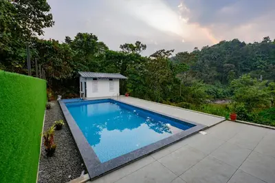 a swimming pool with a small building next to it at Skybz Resort - Mankulam in Viripara