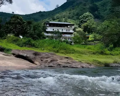 a building on a hill next to a river at Skybz Resort - Mankulam in Viripara