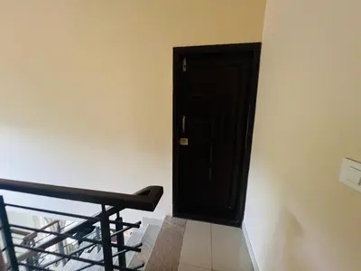a black door in a white wall with a black bench at Green Heaven Mysore Homestay in Mysore