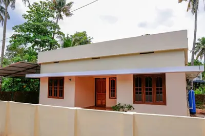 a small house is shown from behind a fence at Orange Villa -3 AC Rooms Near Airport in Ernakulam