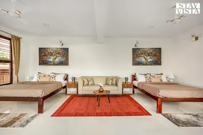 two beds in a room with a couch and a table at StayVista at Hermitage 4BR - Boutique Stay - Relax in Nature in Irpu
