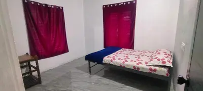a small bed in a room with red curtains at Silent Stays in Kelakam