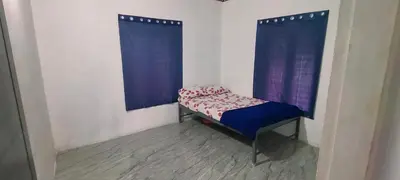 a small bed in a room with blue curtains at Silent Stays in Kelakam