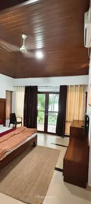 a bedroom with a bed and a chair and windows at BharathaPuzha Resort in Kārakkād