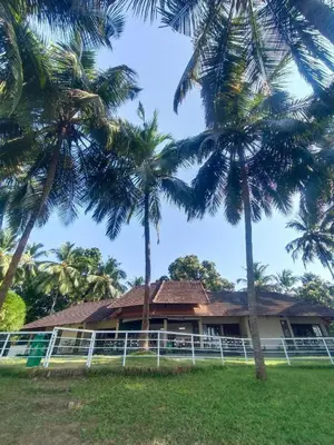 a house with palm trees in front of it at BharathaPuzha Resort in Kārakkād