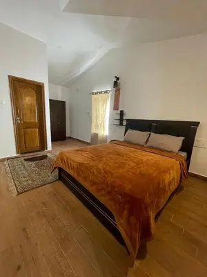 a bedroom with a large bed with a orange blanket at IndivaStays - Moon Stone Villa in Ooty