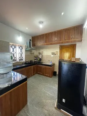 a kitchen with wooden cabinets and a black refrigerator at IndivaStays - Moon Stone Villa in Ooty