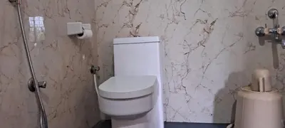 a bathroom with a white toilet and a marble wall at Hill palace Inn in Periya
