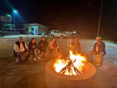a group of people sitting around a fire at night at Coffee Courtyard - Boutique Estate Retreat, Coorg in Kurchi