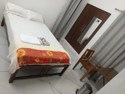 a bedroom with a bed and a wooden door and a chair at Aathira Agri Homes in Trichūr