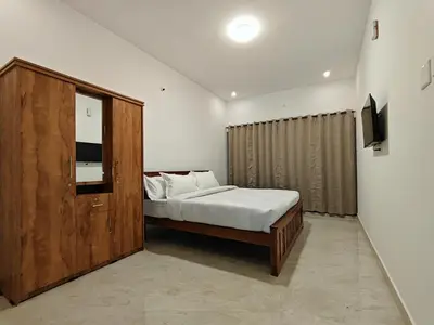 a bedroom with a bed and a wooden cabinet at Mithra Cottages Individual Room's with Balcony in Ooty