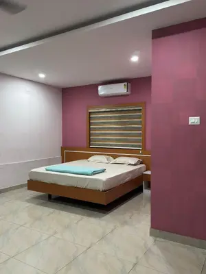 a bedroom with a bed and a purple wall at RV Tourist Home in Ponnāni