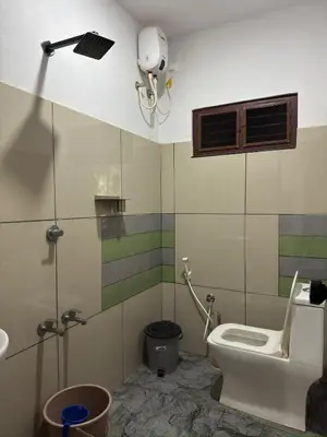 a bathroom with a toilet and a camera on the wall at RV Tourist Home in Ponnāni