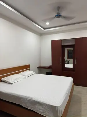 a bedroom with a white bed and a brown cabinet at RV Tourist Home in Ponnāni