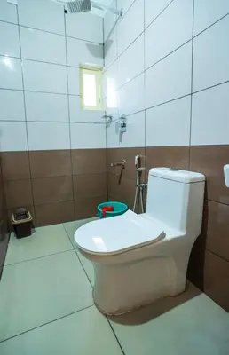 a white toilet in a bathroom with a window at Atholi Residency in Mukkam