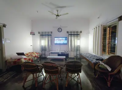 a living room with chairs and a ceiling fan at Anava Farms in Shrīrangapattana
