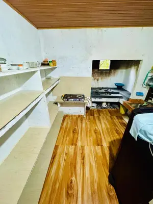 a large kitchen with wooden floors and a fireplace at rivers edge homestay in Viripara