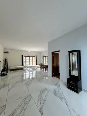 a living room with a marble floor and white walls at Anishanchala in Madikeri