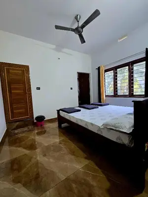 a bedroom with a bed and a ceiling fan at Anishanchala in Madikeri