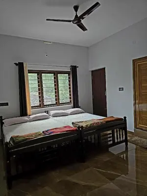 a bedroom with a bed and a ceiling fan at Anishanchala in Madikeri