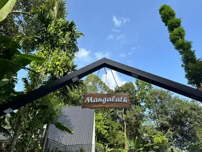 a sign for a restaurant with trees in the background at Mangalath River View Resorts in Kodanad