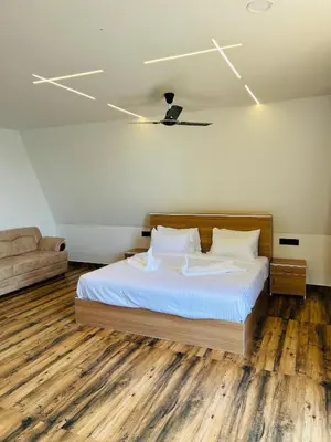 a bedroom with a bed with white sheets and wooden floors at Mangalath River View Resorts in Kodanad