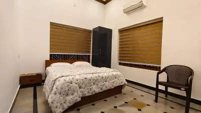 a bedroom with a bed and a chair and two windows at Dreamland kizhunna beach homestay in Kannur