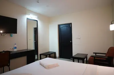 a room with a bed and a desk and a mirror at Wynad Hotel in Kozhikode