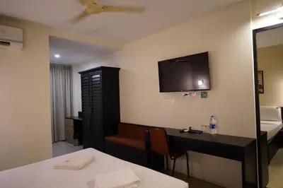 a hotel room with a desk and a tv on the wall at Wynad Hotel in Kozhikode
