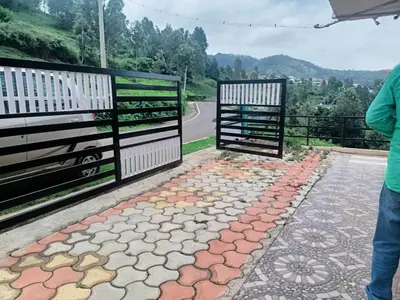 a person standing next to a gate on a road at Greenary homestay in Ooty